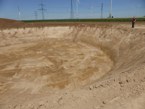 Erdaushebung mit Windrädern im Hintergrund