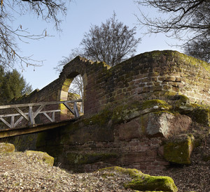 Mauer mit Durchgang und hölzernem Steg