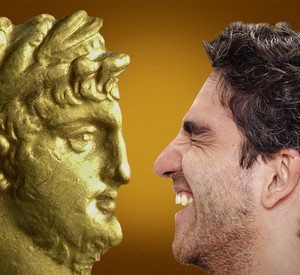 Junger Mann schaut auf den Kopf einer römischen Figur