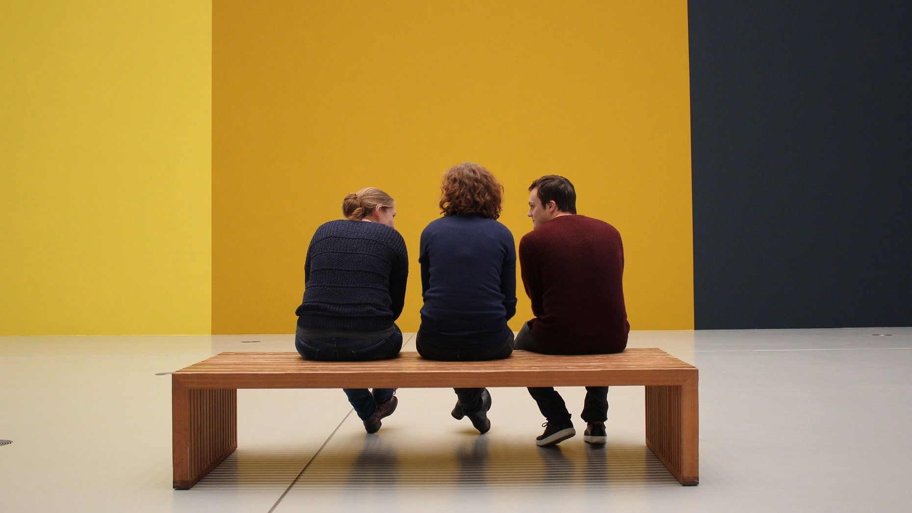 Drei Personen sitzen vor einer gelben Wand