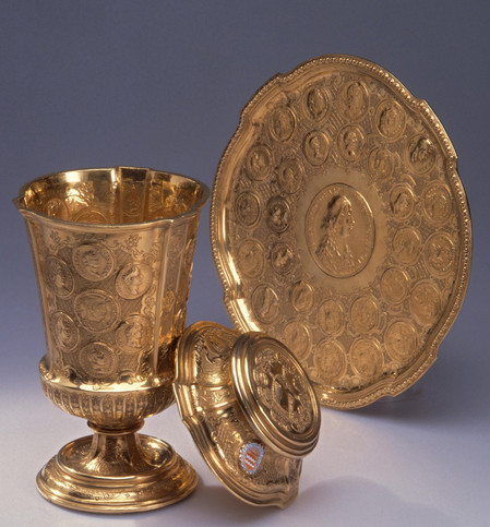 Goldener Becher mit Unterteller, auf die Münzen geprägt sind