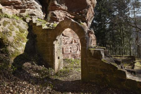 Ruinen eines Portalbogens, der an eine Felswand gebaut ist
