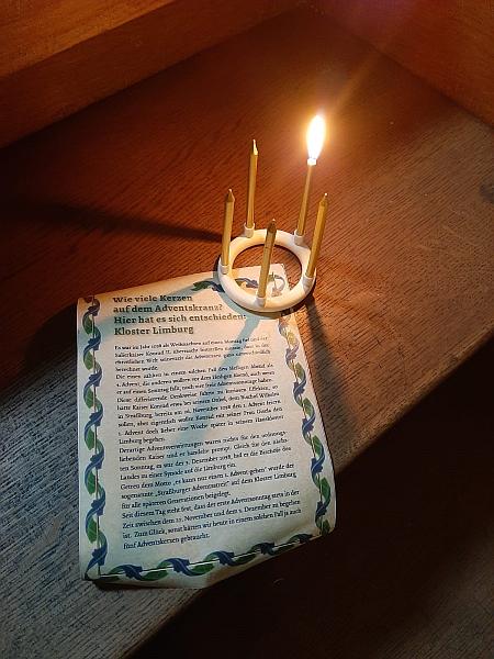 Beschriebenes Blatt Papier neben einem kleinen Kranz mit 5 Kerzen